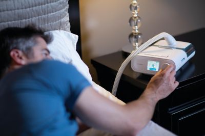 睡眠療法装置「DreamStation」を調整する男性