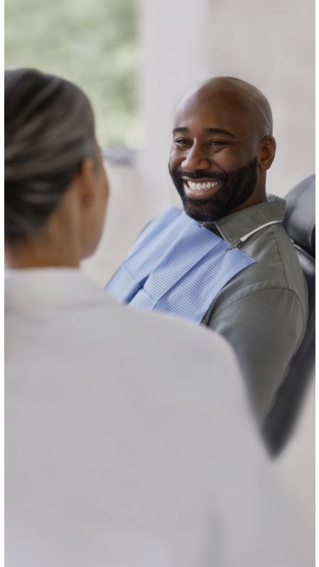 A patient in a dental chair smiling at a dental professional