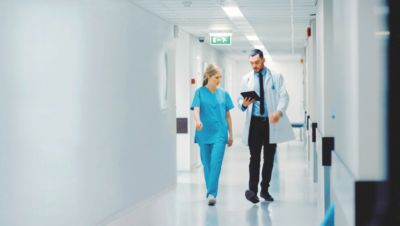 Arts en verpleegkundige lopen door een ziekenhuisgang en bespreken de zorg voor een patiënt