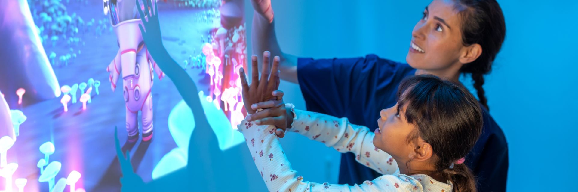 Technician putting patient at easy by playing with Ambient Experience Ollie in Space theme projected on wall prior to an MRI exam.