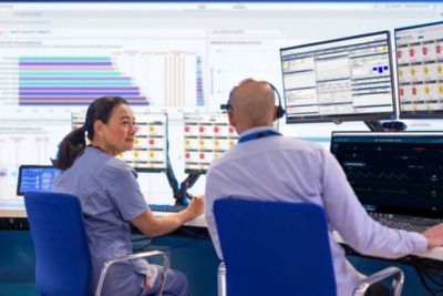 Clinicians monitoring patient data on multiple screens in care unit
