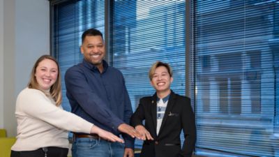 Philips employees standing together with hands stacked in office setting