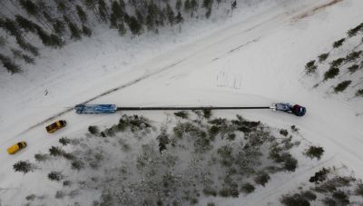 Luftfoto af kranbil på snedækket vej i skov