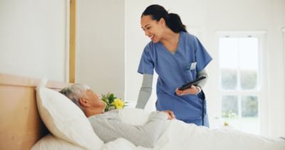 Nurse checking on an older patient resting in a bed during a home care visit