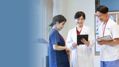  病院の廊下で、タブレットとクリップボードを使って患者情報について話し合う臨床医たち