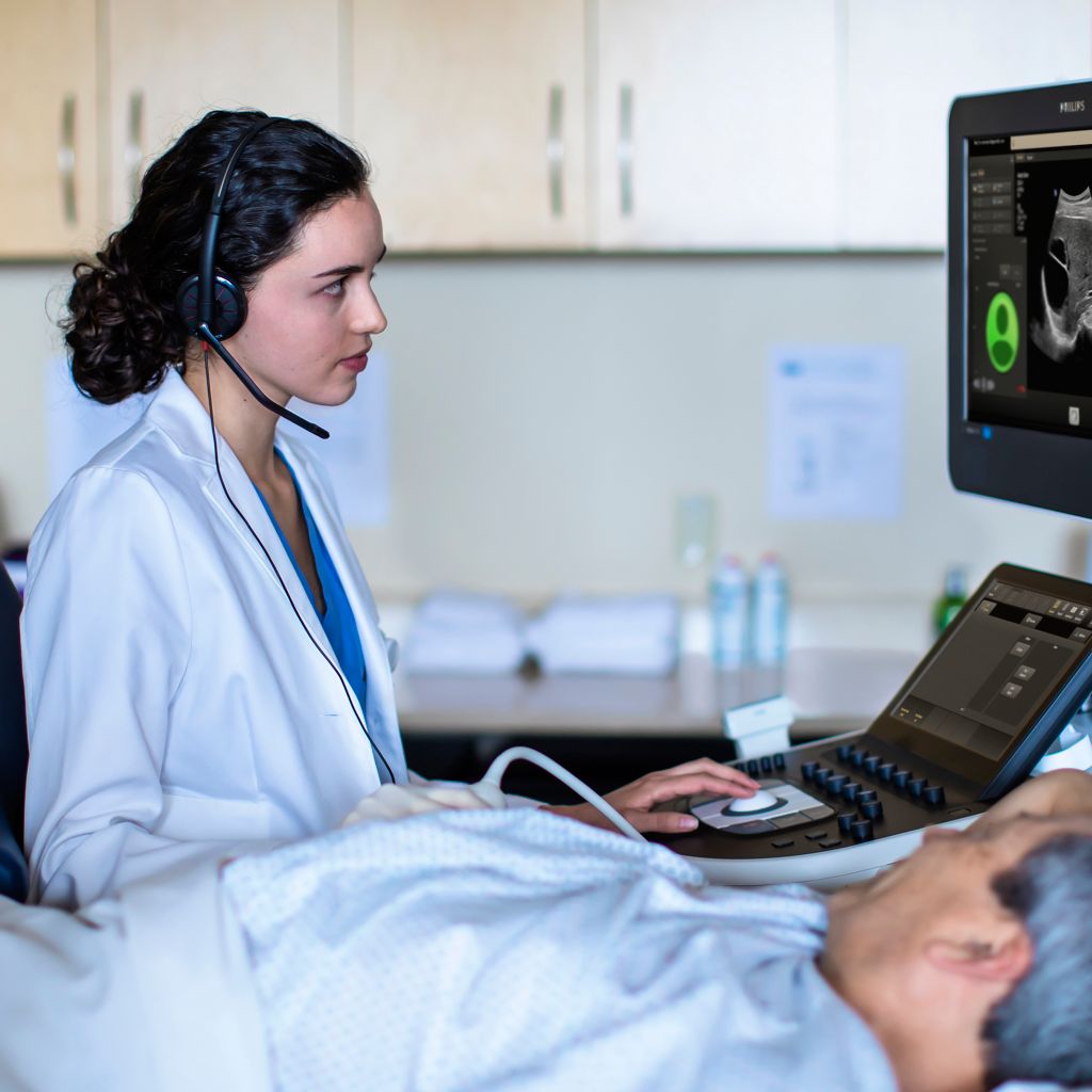 Photo of a female clinician remotely connecting with a specialist via teleultrasound from an ultrasound system while performing an ultrasound exam.