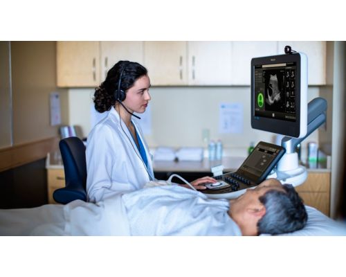 Photo of a female clinician remotely connecting with a specialist via teleultrasound from an ultrasound system while performing an ultrasound exam.  