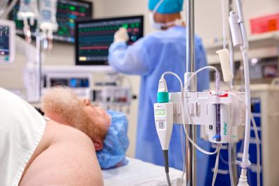 Patient on operating table while clinician checks Philips patient monitoring system in the operating room