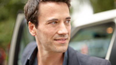 En man med stubbigt sk&auml;gg tittar bort i fj&auml;rran bredvid en &ouml;ppen bild&ouml;rr.