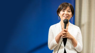 マイクでステージ上で口腔ケアのアドバイスを行う歯科医