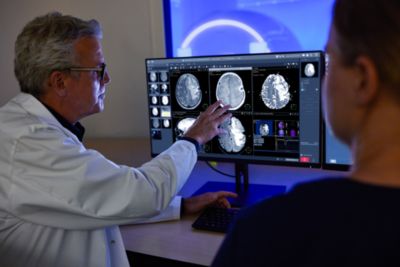 Clinician reviewing brain MRI images on Philips diagnostic workstation with patient
