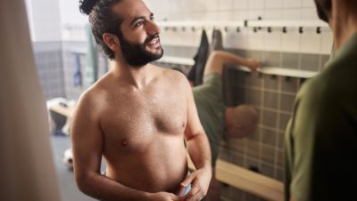 Un deportista musculoso y bien depilado at&aacute;ndose los cordones de las zapatillas en una ciudad.