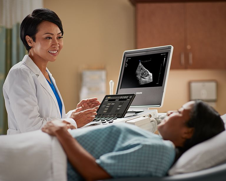 Doctor using the Compact Ultrasound System 5000 series and speaking to a patient in a hospital bed