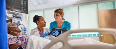 Medical staff interact with a patient at the bedside.