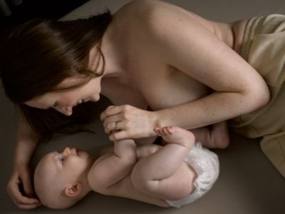 Mutter liegt im Bett und interagiert mit dem Baby