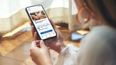 Person holding smartphone using Philips Avent Pregnancy plus app with Arkansas content
