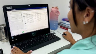 Healthcare professional using Philips Tasy system on desktop computer for patient management