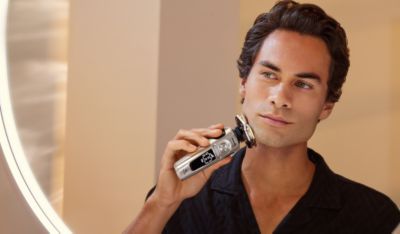 Un primer plano de un hombre joven afeit&aacute;ndose con una m&aacute;quina de afeitar el&eacute;ctrica Philips.