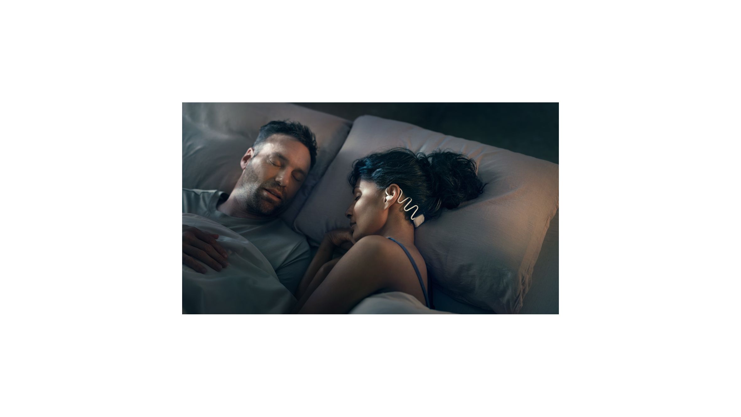 Image of a woman sleeping with Philips Sleep Headphones in to avoid disturbances while sharing a bed with a partner.