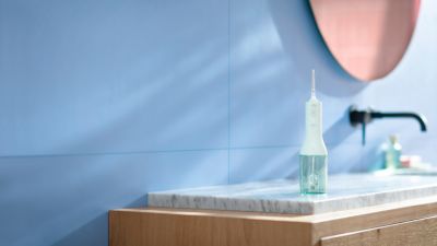 Produktbild der kabellosen Philips Sonicare Munddusche in Wei&szlig; auf einer Badezimmerarmatur.