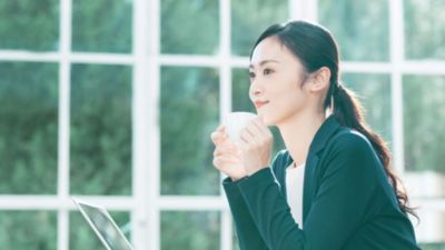 窓辺でコーヒーを飲む女性