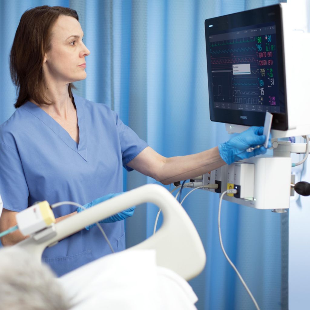 Woman in scrubs looking at vitals on monitor