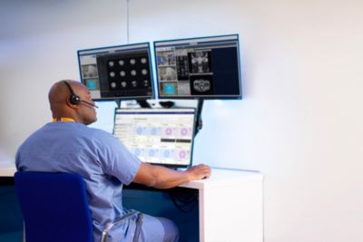 Radiologist monitoring imaging data on multiple screens in ROCC command center