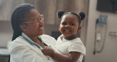 Clinician holding a smiling toddler during a pediatric checkup