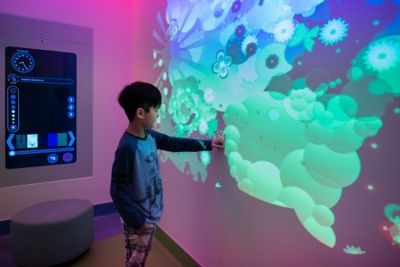 Pediatric patient interacting with immersive wall projection in Ambient Experience room