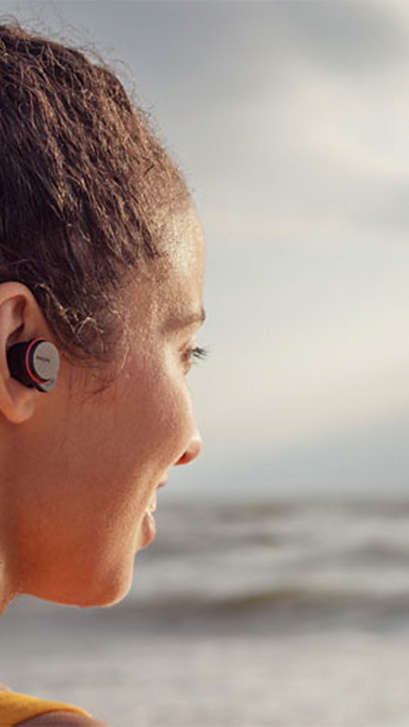 Frau, die True Wireless Kopfhörer am Meer verwendet