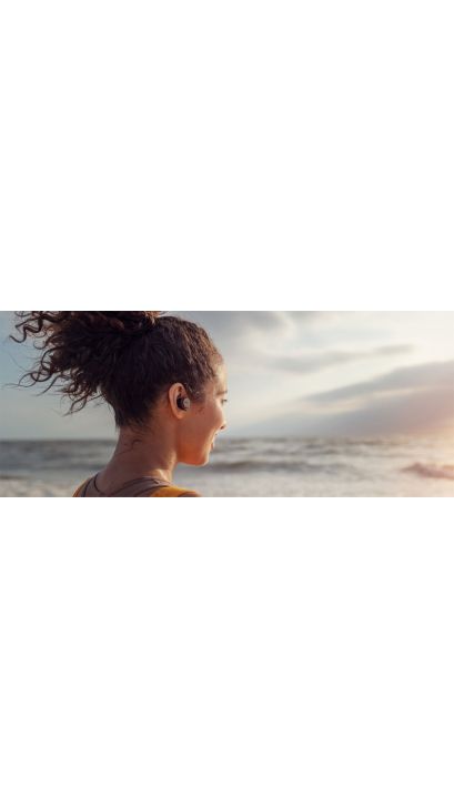 Vrouw met echte draadloze hoofdtelefoons aan zee