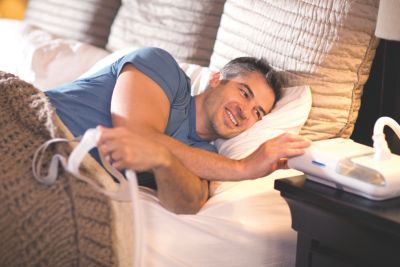 Man using Philips DreamStation sleep therapy device in bed