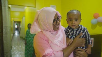 Health worker partnered with BRAC holding a baby in a healthcare center in Bangladesh