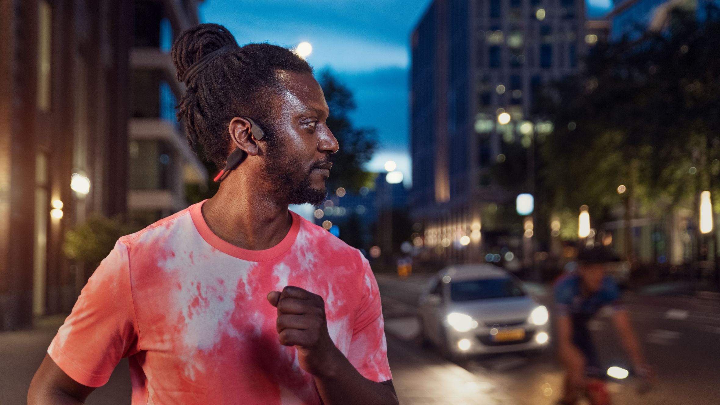 Csontvezető fejhallgat&oacute;t haszn&aacute;l&oacute; sportol&oacute; egy forgalmas utc&aacute;n