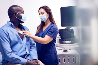Medical professional applying cardiac monitoring patch to patient using Philips system