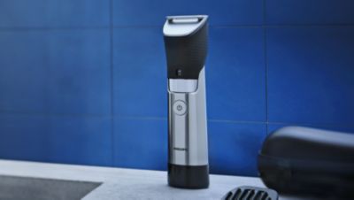 Een Philips-baardtrimmer op een badkamermeubel naast de wastafel.