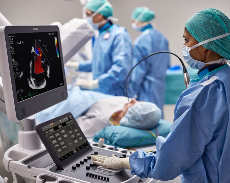 Clinicians performing transesophageal echo exam on a patient in an interventional suite.