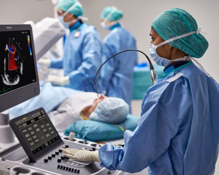 Clinicians performing transesophageal echo exam on a patient in an interventional suite.