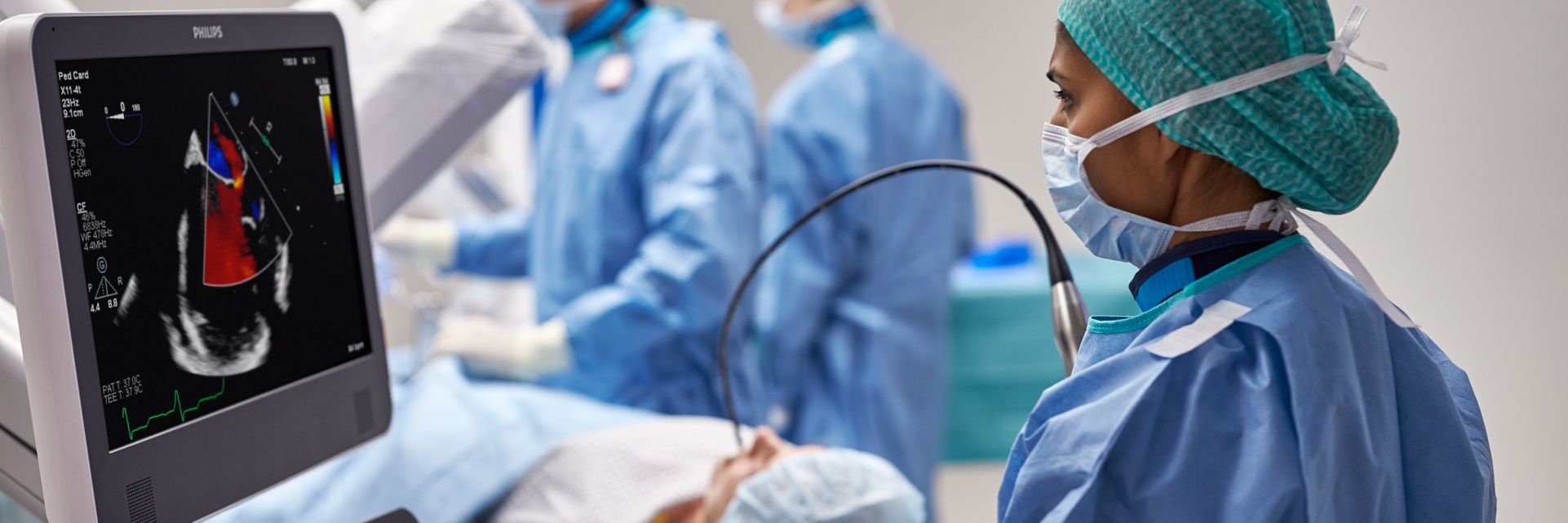 Clinicians performing transesophageal echo exam on a patient in an interventional suite.