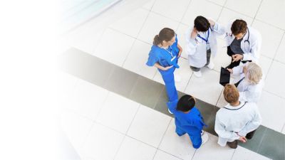 Zespół medyczny stojący na szpitalnym korytarzu rozmawiający o opiece nad pacjentem