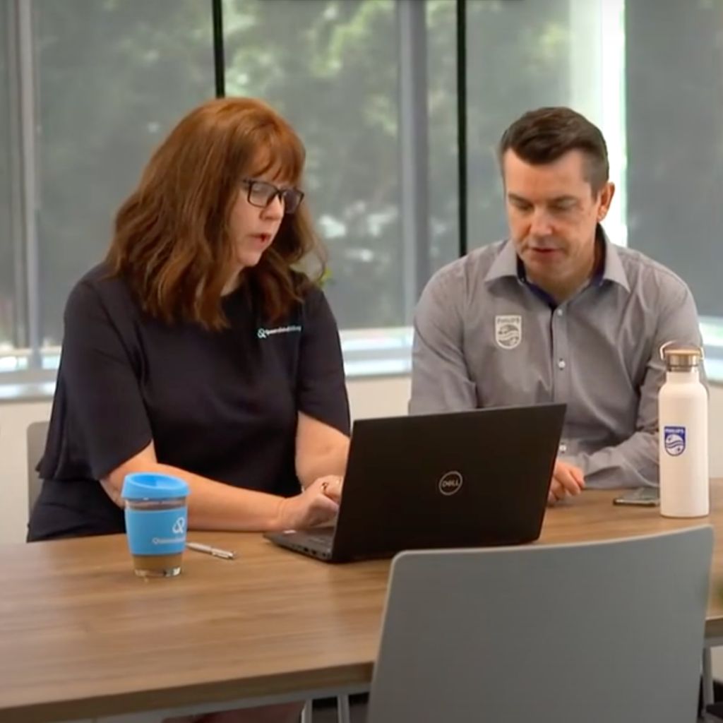 Two people looking at laptop screen in conference room