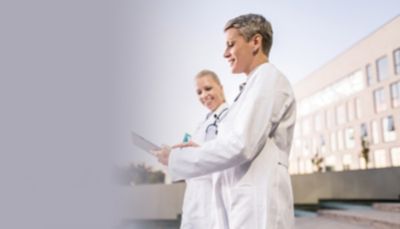 Clinicians outside a hospital using a tablet