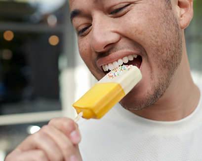 A man biting into a popsicle