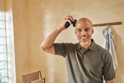 Man shaving head with Philips Norelco rotary head shaver