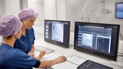 Profissional de saúde e colega revisando informações em um tablet no corredor do hospital