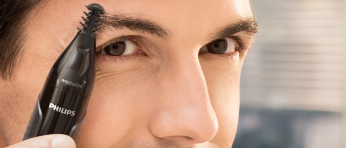 A man shapes his eyebrows using the Philips Nose Trimmer, ideal for brow shaping for men.