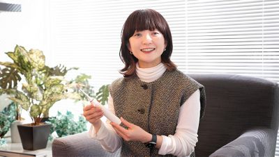 窓際でソニッケアーの歯ブラシを手に微笑む女性