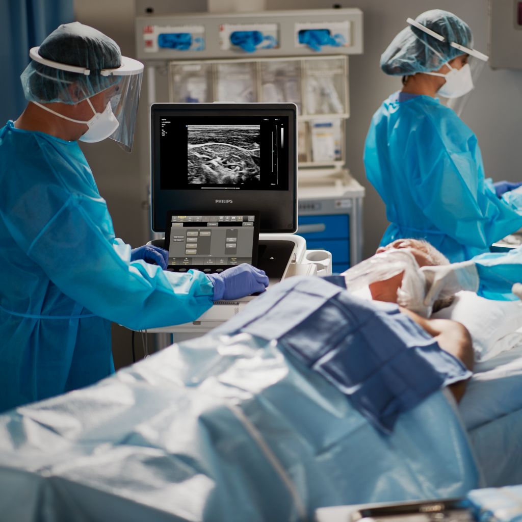 Patient in anesthesia setting with clinicians consulting mobile ultrasound system