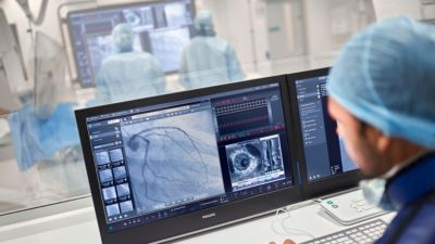 Clinician reviewing coronary angiography and IVUS images on workstation in cath lab