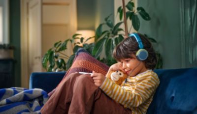 Child wearing wired headphones while relaxing on sofa